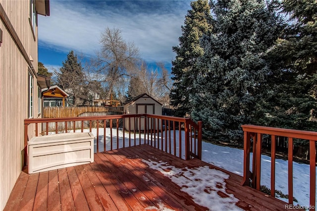 wooden terrace featuring an outdoor structure, fence, and a storage unit