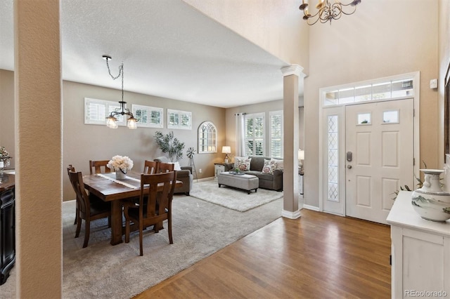 dining room featuring ornate columns, baseboards, a notable chandelier, and wood finished floors