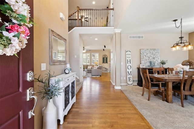 foyer with a ceiling fan, baseboards, visible vents, light wood-style floors, and ornate columns