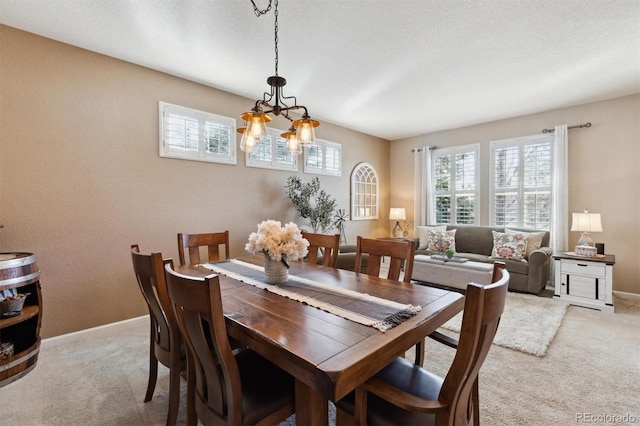 dining space with baseboards, a textured ceiling, and light colored carpet