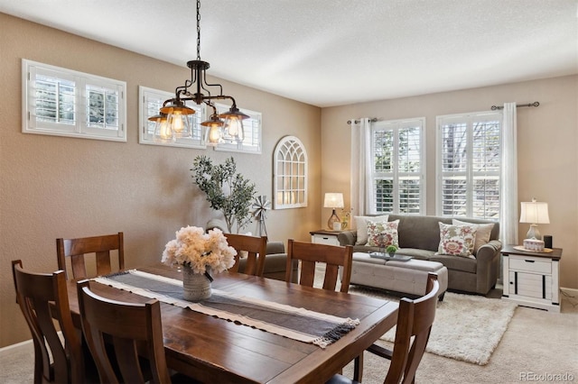 carpeted dining room featuring a notable chandelier and a textured ceiling