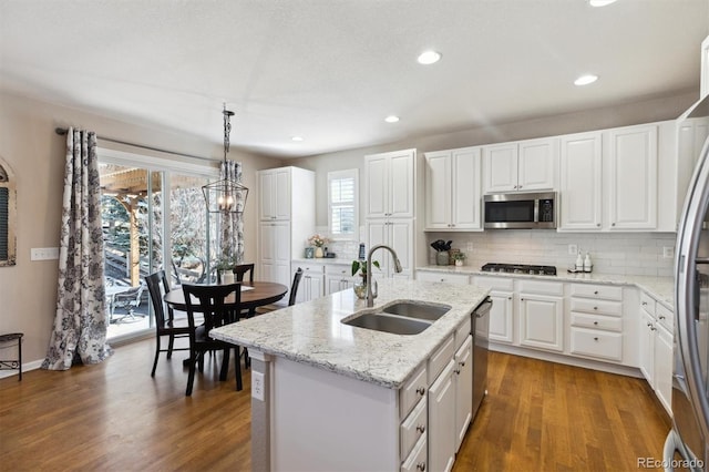 kitchen featuring stainless steel appliances, dark wood-type flooring, a sink, white cabinetry, and tasteful backsplash