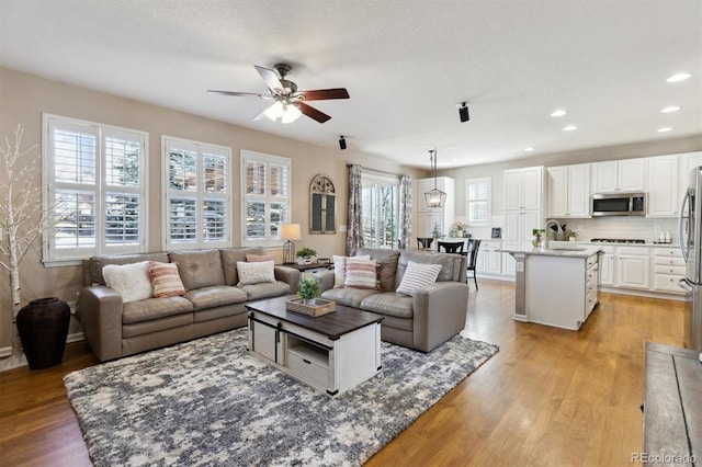 living room with light wood finished floors, a textured ceiling, a ceiling fan, and recessed lighting