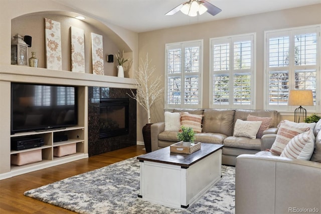 living area featuring wood finished floors, a high end fireplace, and a ceiling fan