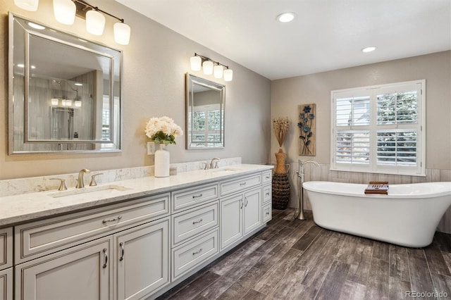 full bath featuring double vanity, a wainscoted wall, a sink, and wood finished floors