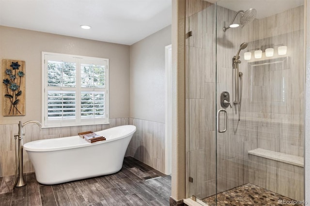 full bathroom featuring wainscoting, wood finished floors, a freestanding tub, and a shower stall