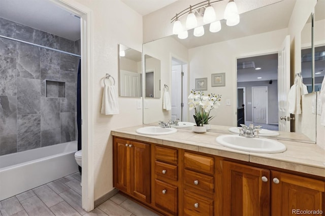 bathroom with double vanity, toilet, a sink, and wood finish floors