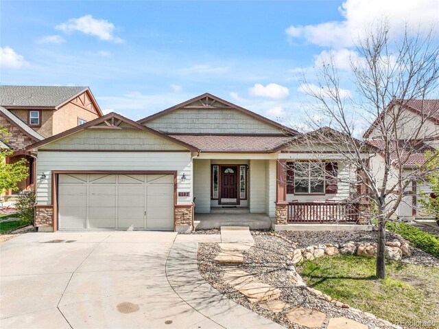 4197 Purple Plum Way, Colorado Springs, CO 80920 - view of front facade with covered porch, an attached garage, concrete driveway, roof with shingles, and stone siding