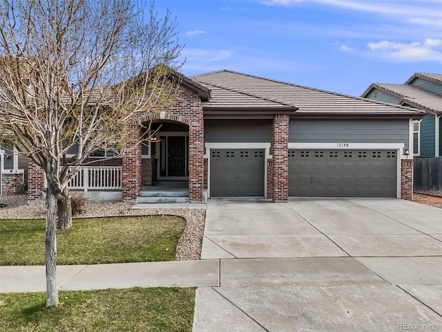 view of front of property featuring an attached garage, a tile roof, brick siding, and driveway
