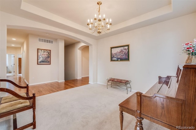 living area featuring arched walkways, a tray ceiling, and visible vents