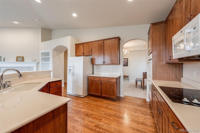 kitchen with white appliances, arched walkways, a sink, and brown cabinets