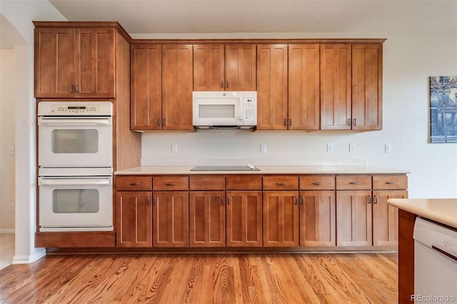 kitchen featuring light countertops, brown cabinets, and white appliances
