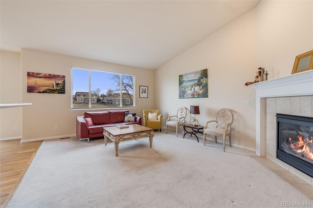 carpeted living room featuring baseboards, high vaulted ceiling, and a tile fireplace