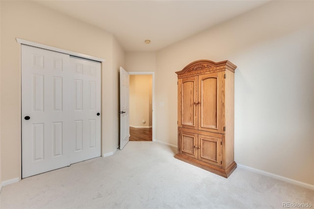 unfurnished bedroom featuring baseboards, a closet, and light colored carpet