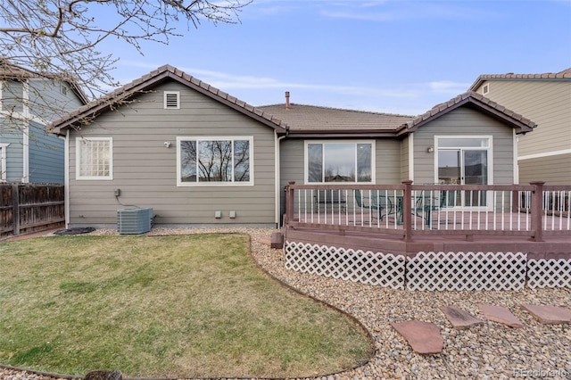 back of house with fence, a wooden deck, a tiled roof, central AC, and a lawn