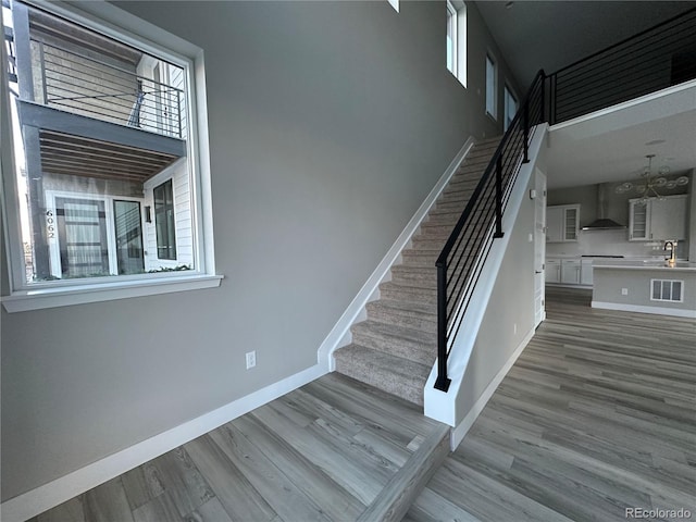 staircase featuring a healthy amount of sunlight, sink, and wood-type flooring