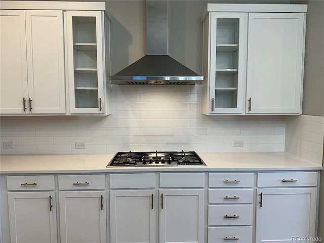 kitchen with white cabinetry, backsplash, stainless steel gas cooktop, and wall chimney exhaust hood