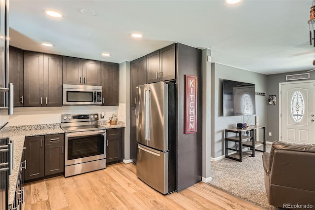 3180 Mowry Pl, Westminster, CO 80031 - kitchen with dark brown cabinets, light wood-type flooring, baseboards, appliances with stainless steel finishes, and light stone countertops