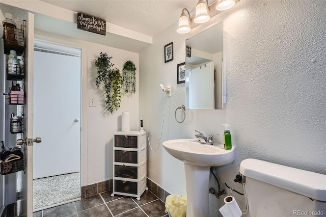 3180 Mowry Pl, Westminster, CO 80031 - bathroom featuring tile patterned floors, a textured wall, toilet, a sink, and baseboards