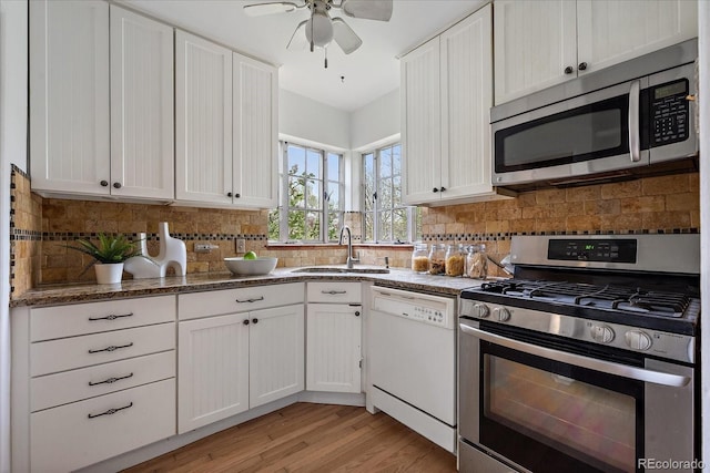1439 Dexter St, Denver, CO 80220 - kitchen featuring appliances with stainless steel finishes, a sink, decorative backsplash, and white cabinets