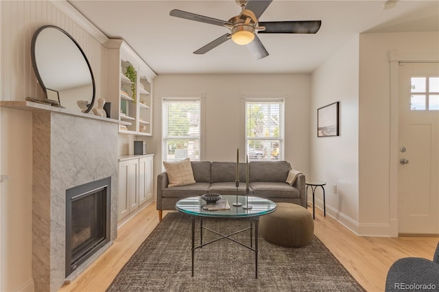 living room featuring light hardwood / wood-style floors, a fireplace, ceiling fan, and a wealth of natural light