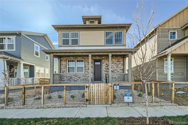 view of front of property with stone siding, a porch, a fenced front yard, and a gate