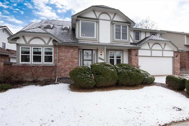 tudor house featuring driveway, brick siding, an attached garage, and stucco siding