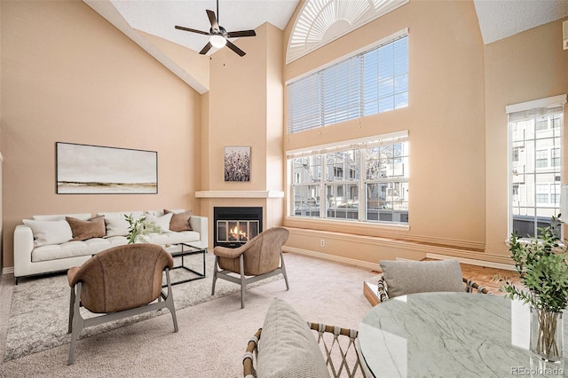 carpeted living room featuring ceiling fan, a fireplace, and high vaulted ceiling