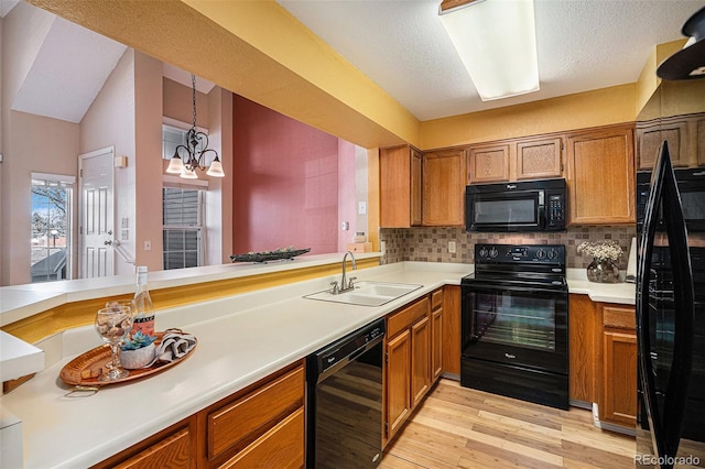 kitchen featuring kitchen peninsula, tasteful backsplash, a chandelier, black appliances, and sink