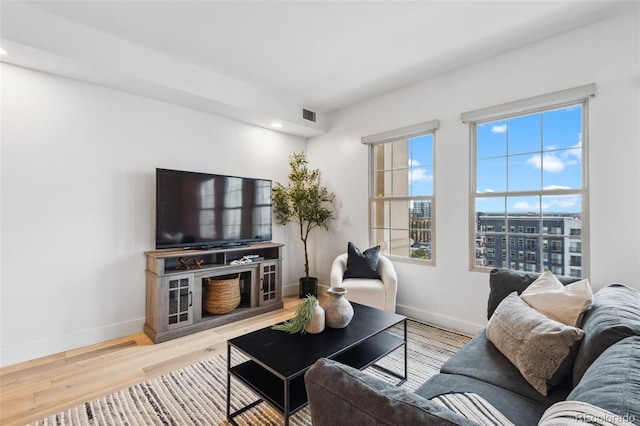 living area with visible vents, baseboards, and wood finished floors