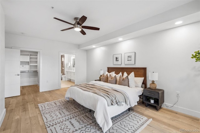 bedroom featuring light wood finished floors, recessed lighting, a spacious closet, connected bathroom, and baseboards