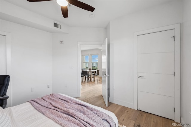 bedroom featuring light wood finished floors, a ceiling fan, visible vents, and baseboards