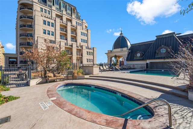 community pool featuring a patio area, fence, and a community hot tub