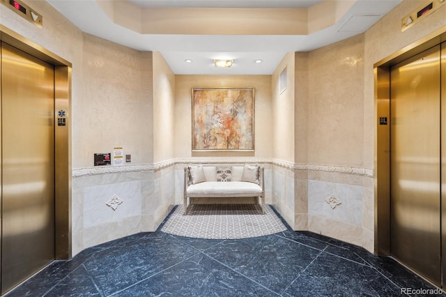 interior space featuring a wainscoted wall, tile walls, and elevator