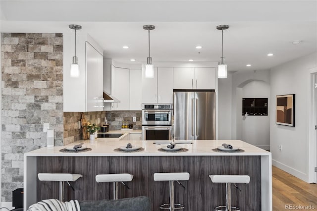 kitchen with stainless steel appliances, hanging light fixtures, and a breakfast bar area