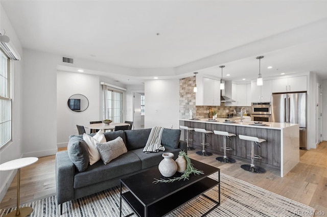 living room with light wood finished floors, visible vents, and recessed lighting