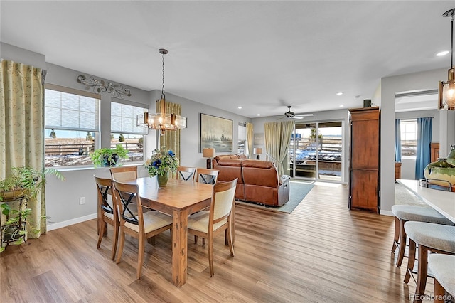 dining area featuring ceiling fan with notable chandelier and light hardwood / wood-style floors