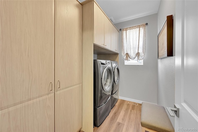 laundry room featuring cabinets, separate washer and dryer, and light hardwood / wood-style flooring