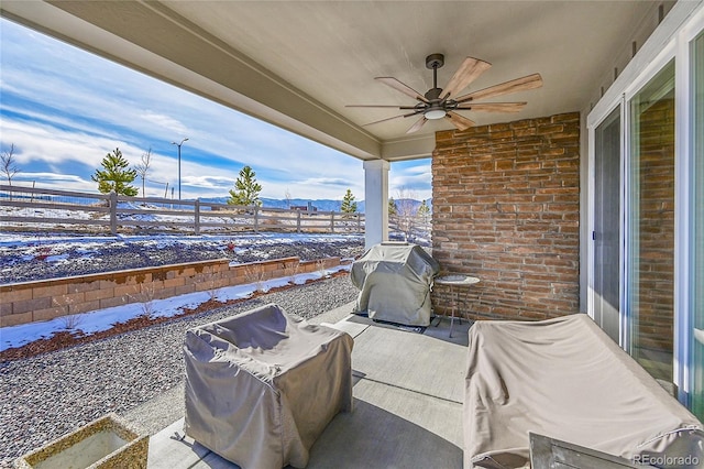 snow covered patio featuring area for grilling and ceiling fan