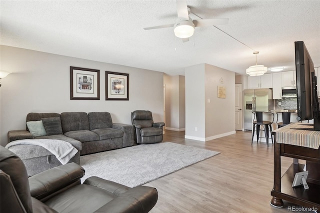 3465 S Poplar St Unit 305, Denver, CO 80224 - living room featuring a ceiling fan, a textured ceiling, light wood-style flooring, and baseboards