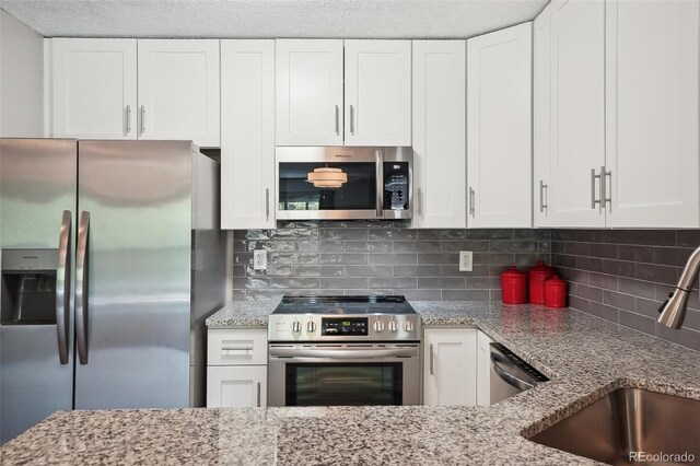 3465 S Poplar St Unit 305, Denver, CO 80224 - kitchen with appliances with stainless steel finishes, a sink, white cabinetry, backsplash, and light stone counters