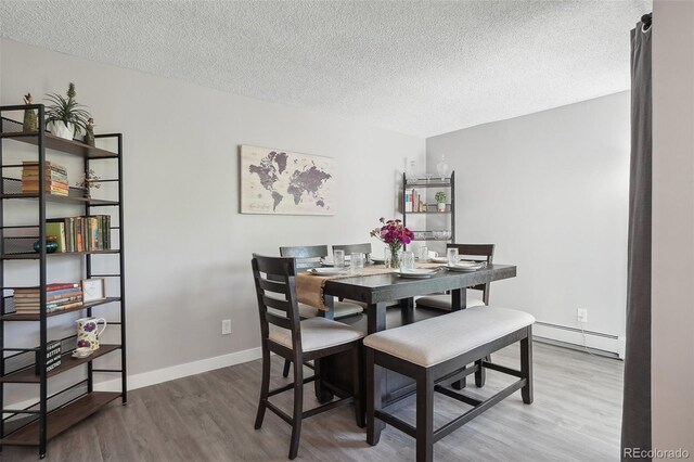 3465 S Poplar St Unit 305, Denver, CO 80224 - dining space with a baseboard radiator, a textured ceiling, wood finished floors, and baseboards