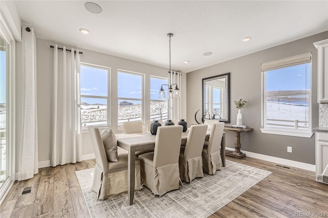 dining space featuring light hardwood / wood-style floors, a wealth of natural light, and a notable chandelier