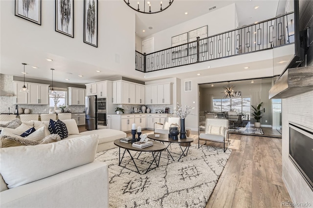 living room with light hardwood / wood-style floors, a high ceiling, and a chandelier