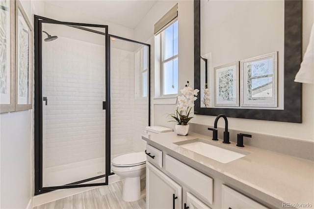 bathroom featuring wood-type flooring, vanity, toilet, and a shower with door