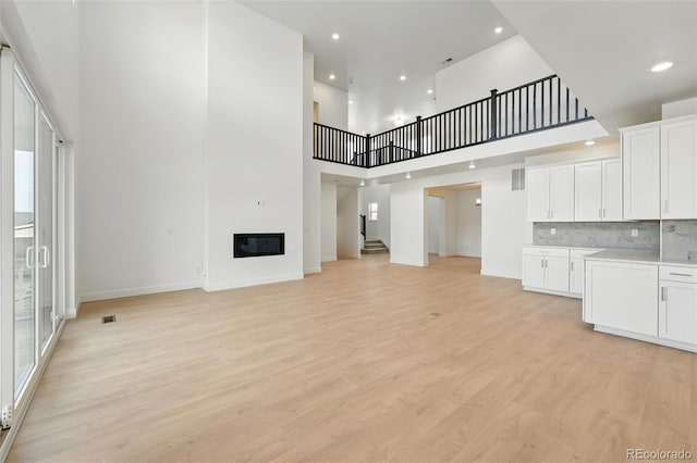 16537 Black Rose Cir, Parker, CO 80134 - unfurnished living room featuring baseboards, stairs, recessed lighting, light wood-style floors, and a glass covered fireplace