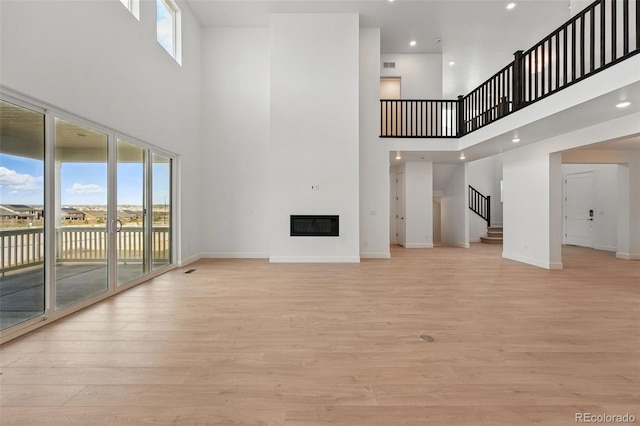 16537 Black Rose Cir, Parker, CO 80134 - unfurnished living room with light wood-style flooring, baseboards, stairway, and a glass covered fireplace