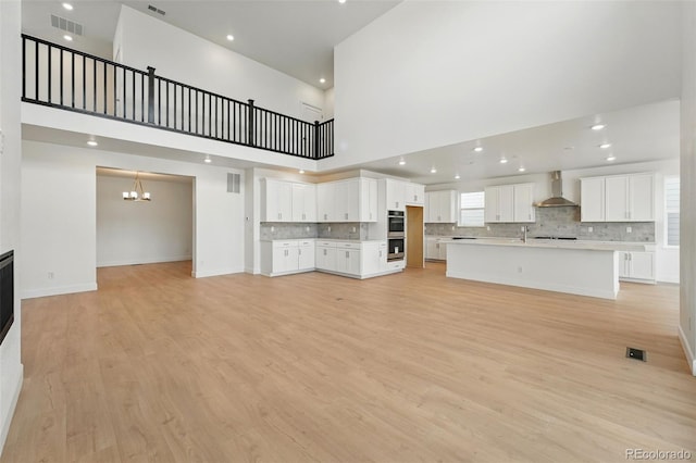 16537 Black Rose Cir, Parker, CO 80134 - unfurnished living room featuring a notable chandelier, a sink, light wood finished floors, baseboards, and visible vents