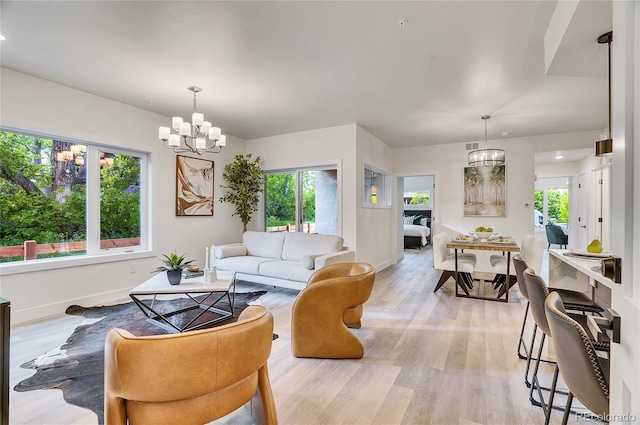 living room featuring a notable chandelier, plenty of natural light, and light hardwood / wood-style flooring