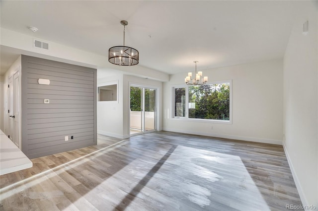 unfurnished living room with a notable chandelier and light wood-type flooring